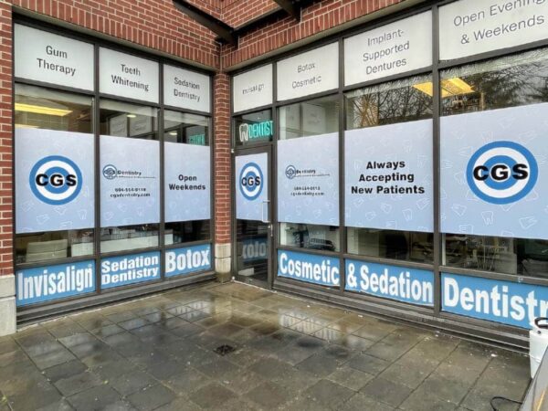Exterior view of a dental office featuring large windows with signage promoting services such as Invisalign, Botox, and sedation dentistry. The office is welcoming to new patients, and the design highlights its cosmetic offerings.