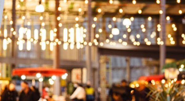 A lively venue is illuminated by warm lights, with people mingling and enjoying the atmosphere. In the foreground, a hint of greenery adds to the inviting scene. The 123Dentist Smiley brings a friendly touch to this vibrant gathering.