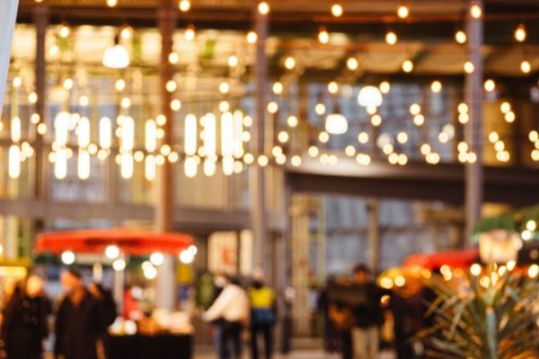 A lively venue is illuminated by warm lights, with people mingling and enjoying the atmosphere. In the foreground, a hint of greenery adds to the inviting scene. The 123Dentist Smiley brings a friendly touch to this vibrant gathering.