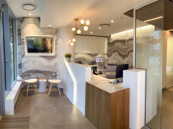 A modern reception area featuring a sleek front desk, contemporary lighting, and a comfortable seating space. The walls have a stylish marble design, creating a welcoming atmosphere for visitors.