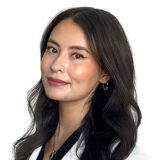 A friendly woman with long dark hair wears a white coat. She smiles and looks directly at the viewer, exuding warmth and professionalism.