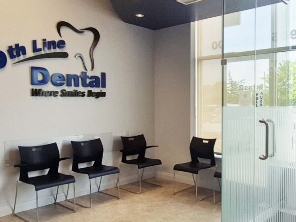 Interior of a dental clinic featuring the sign "9th Line Dental." The waiting area includes several black chairs and a glass door leading outside, creating a modern and welcoming atmosphere.