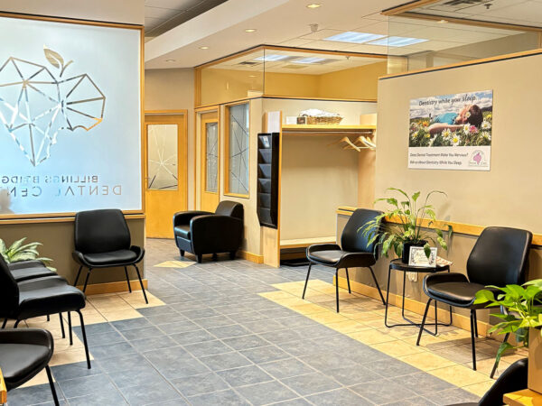 A clean and modern dental office waiting room featuring black chairs, greenery, and a welcoming atmosphere. The 123Dentist Smiley adds a friendly touch, making the space feel inviting for patients.