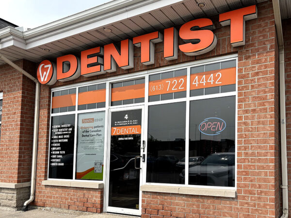 A dental clinic storefront featuring a large "DENTIST" sign in orange. The windows display informational signage and contact details, creating a welcoming appearance.