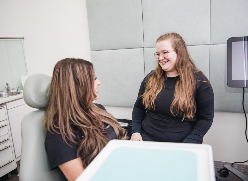 A dental professional and a patient share a light-hearted moment in a bright, inviting dental office. The 123Dentist Smiley is present, creating a cheerful atmosphere.