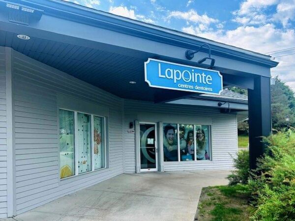 A modern storefront of Lapointe, featuring large windows and a bright blue sign with the business name. The exterior is well-maintained, surrounded by green landscaping and under a partly cloudy sky.