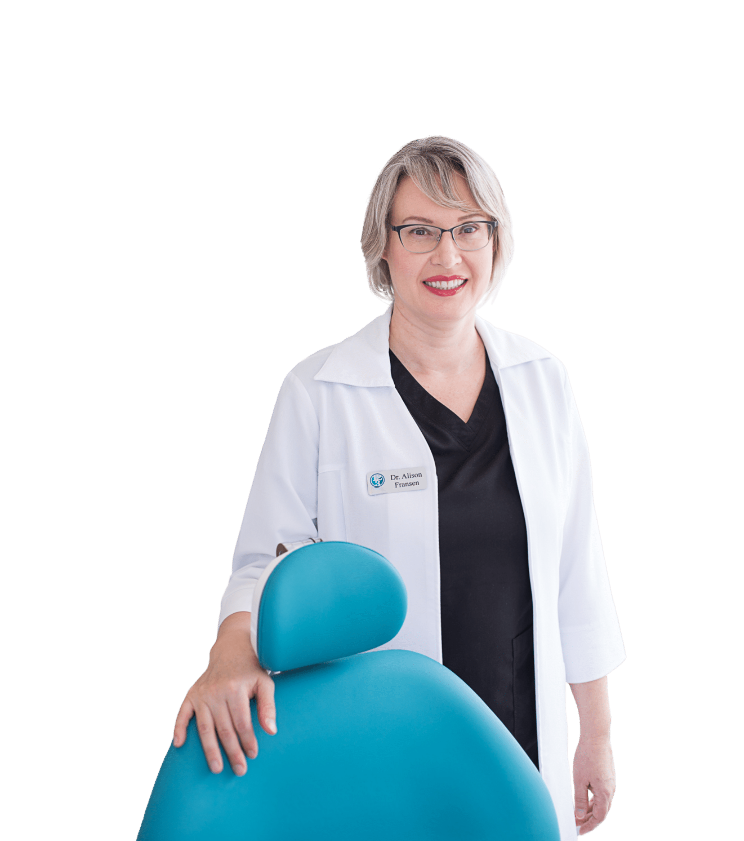 A smiling dental professional in a white coat stands beside a bright turquoise dental chair, exuding a warm and welcoming demeanor. The background is neutral, focusing attention on her friendly expression and the inviting atmosphere of a dental practice.